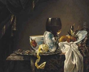 A still life of china, a goblet, fruit and a peeled lemon on a table by Willem Kalf