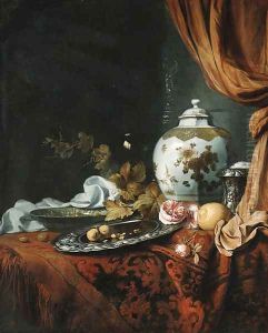 A blue and white facetted vase with other dishes, glasses, fruit and roses on a draped table