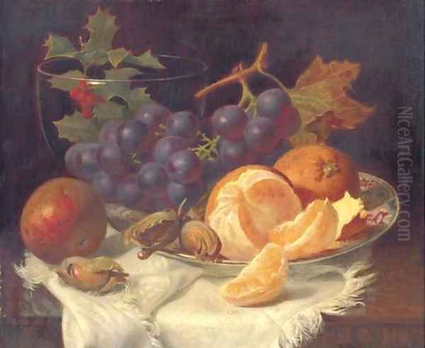 An apple, black grapes, two oranges and cob nuts on oriental plate, with holly in a glass vase, on a wooden table - view 1