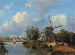 A Windmill Along A Canal With A Town In The Distance