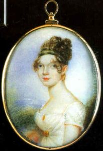 A Young Lady Wearing A White Dress Clasped With Gold Brooch & Earings
