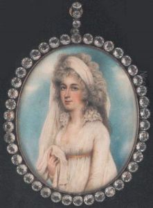 A Lady Wearing Decollete White Dress With Frilled Collar And Yellow Ribbon, Drop Earring And Long White Veil Falling Over Her Shoulder And Held In Her Right Hand