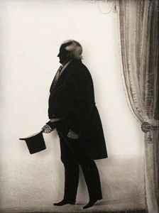 Colonel Reid Wearing Tail-coat And Gloves, He Holds A Top Hat In His Right Hand, Tied Curtain To The Right by John Woodhouse