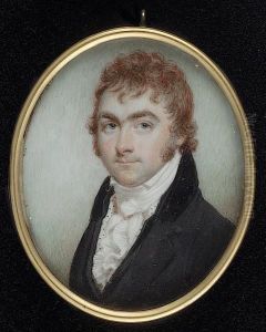 A Gentleman, With Red Hair, Wearing Dark Grey Coat With Black Collar, Matching Waistcoat With White And Black Spotted Lining, Frilled Shirt And Cravat