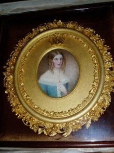 A Portrait Of A Young Lady, Her Fair Hair In Ringlets And Wearing A Blue Gown With Lace Trimming And Gold Jewellery A Portrait Of A Young Lady, Her Fair Hair In Ringlets And Wearing A Blue Gown With Lace Trimming And Gold Jewellery