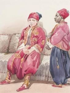 Un Jeune Garcon Oriental Assis Sur Un Canape Avec Un Jeuneserviteur Noir De Profil A Droite by Antoine Alphonse Montfort